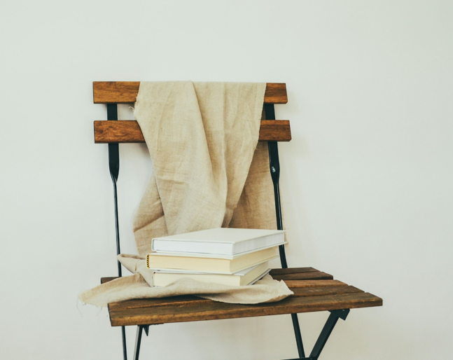 A small stack of books on a wooden folding chair, representing recommended reading on Korea–Japan relations, history, and dialogue beyond nationalism